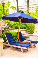 Beach chairs with umbrellas in exotic resort near swimming pool