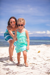 Little girl and young mother having fun on tropical beach