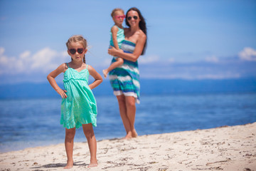 Adorable little girls and young mother on tropical white beach