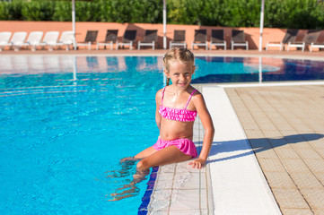 Adorable happy little girl in the swimming pool outside