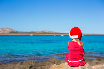 Adorable little girl in christmas hat during beach vacation