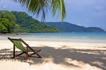 Tropical beach. Beach chairs on the white sand beach, foreground