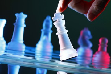Finger tilting a chess piece on Chess Board © junpinzon