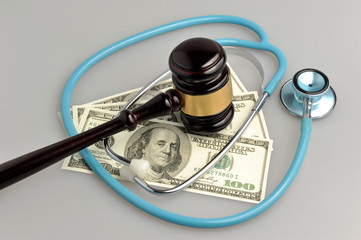 Stethoscope with judge gavel, money on gray