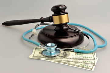 Stethoscope with judge gavel, money on gray background