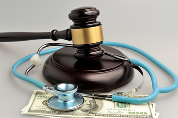 Stethoscope with judge gavel, money on gray background