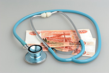 Stethoscope and money on gray