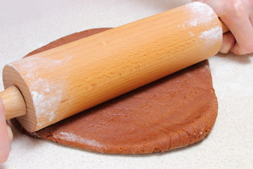 Hands of woman with rolling pin and dough for Christmas cookies