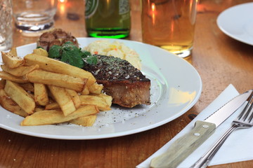 Piece of steak with french fries, cole slaw and fried garlic.