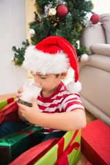 Cute boy in large christmas present drinking milk