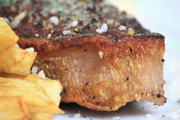 Piece of steak with chips on a plate.