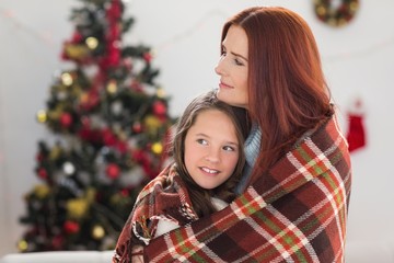 Festive mother and daughter wrapped in blanket