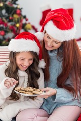 Festive mother and daughter on the couch with cookies