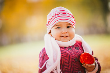 Little girl eating apple in autumn