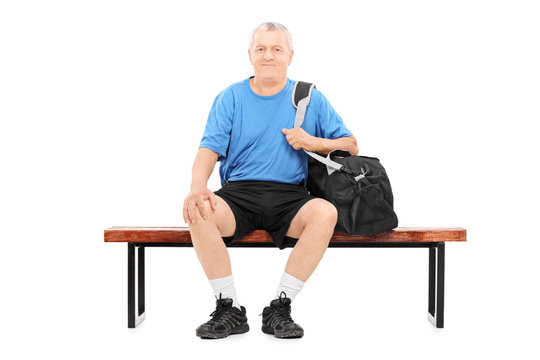 Active Senior Carrying A Sports Bag Seated On Bench