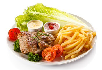 Barbecued steak, French fries and vegetables