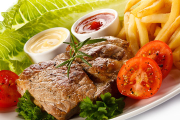 Barbecued steak, French fries and vegetables