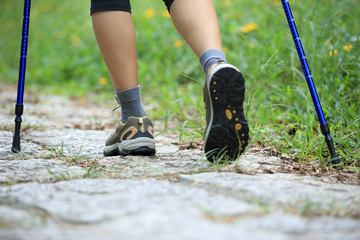 young fitness woman hiker legs walking on green grass trail 