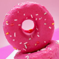 donuts coated with a pink frosting and sprinkles of different co