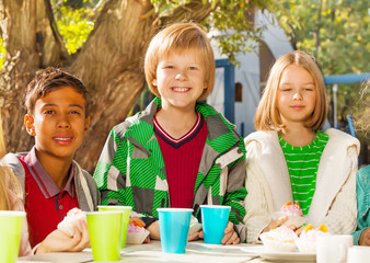 Happy children diversity sitting at table outside