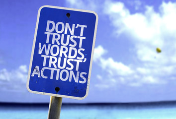 Don't Trust Words, Trust Actions sign with a beach