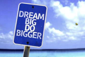 Dream Big Do Bigger sign with a beach on background