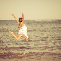 teen girl jumping on the beach at the day time