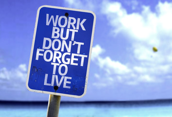 Work But Don't Forget to Live sign with a beach on background