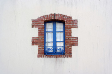Blue Window frame edged with bricks in Brittany