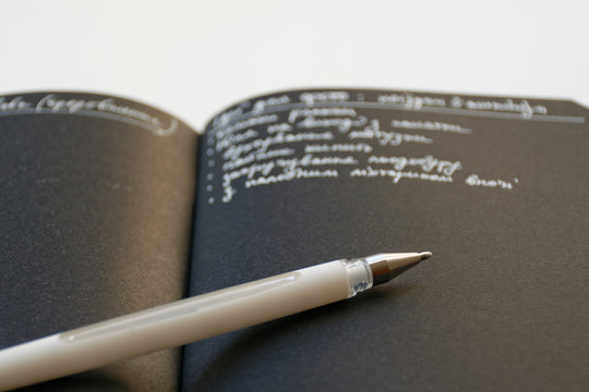 Notebook with black paper and white pen opened