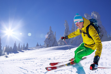 Skier skiing in high mountains against blue sky