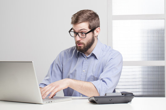Young businessman in shock looking at his laptop