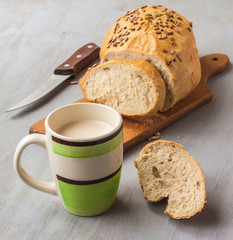 Loaf of rye bread sunflower seeds on a cutting board and cup of