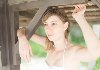 Beautiful young woman under wooden pier on beach.