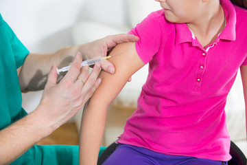 Doctor giving vaccination injection to little girl patient