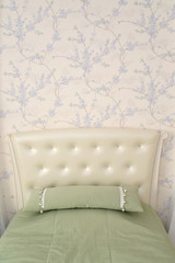 Headboard of a single bed with a throw pillow. Modern classics w