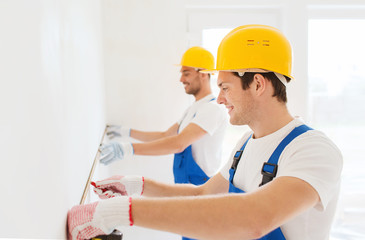 smiling builders with measuring tape indoors