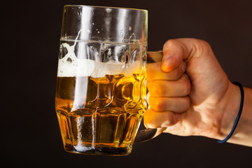Male hand holding mug of beer