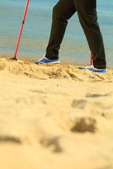 active woman senior nordic walking on a beach. legs