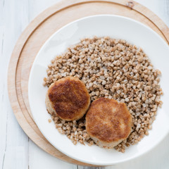Glass plate with buckwheat and meat cutlets, view from above