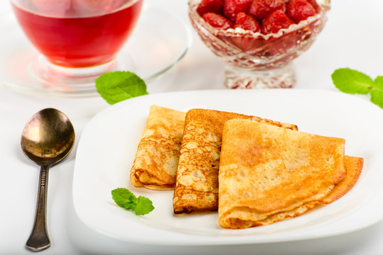 Traditional Russian pancakes with black tea and strawberries.