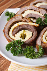 Meat roll with egg and cucumber closeup on a white plate
