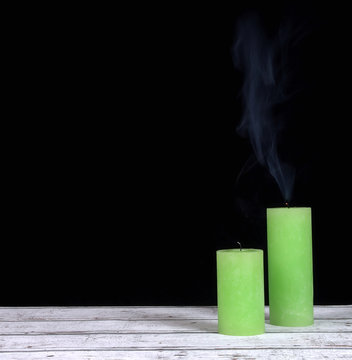 Smoke and extinct green candles on a black background