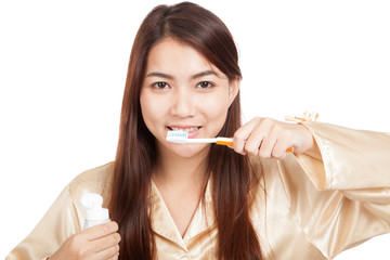 Asian woman in pajamas with toothbrush and toothpaste