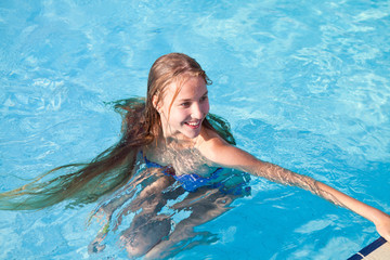 Блондинка с длинными волосами плавает в бассейне