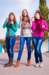 Three young beautiful women blow bubbles