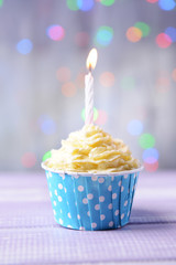 Delicious birthday cupcake on table on light background