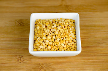 Aerial closeup of yellow split peas in white bowl