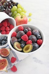 Seasonal fruits and berries in a white vintage bowl .