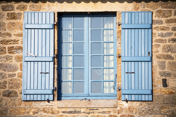 blue shutters on medieval stone wall, France - 72821105